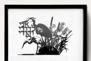 Jewish papercut, nature papercut, 2 herons sitting at the water's edge. Ani Ledodi Vidodi Li suspended between the 2 herons; Song of Songs